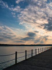 Fototapeta na wymiar Late afternoon over a pier. Blue and orange sky over a lake. Late afternoon over a lake side.