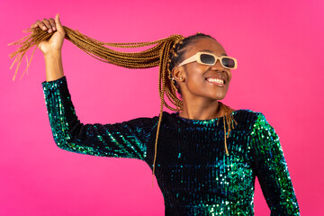 A black ethnic woman with braids party dancing on a pink background, having a lot of fun