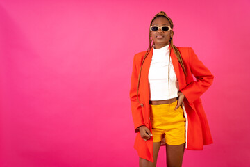African young woman with braids on a pink background, portrait in a red suit and yellow pants