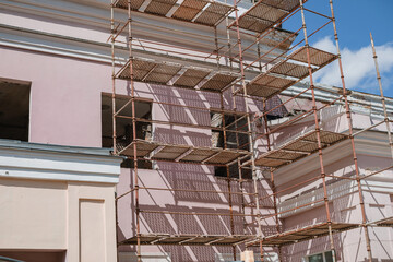 Unrecognizable fragment of a building in scaffolding. Restoration of the building. Sunny day.