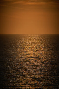 A vertical photograph of a moody dark orange sea view