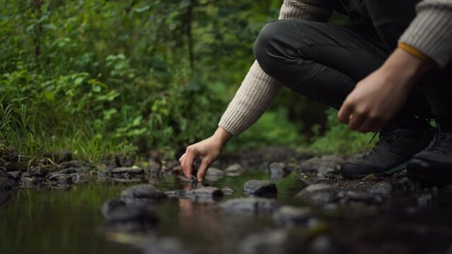 Close up of male hands collecting water samples from natural water stream.