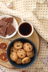 Various Christmas decorations, cup of tea or coffee, sweets, small presents, knitted blanket and candles. Flat lay.