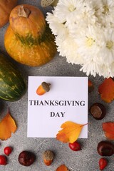 Thanksgiving day, holiday celebrated every fourth Thursday in November. Flat lay with paper card and autumn leaves on grey table