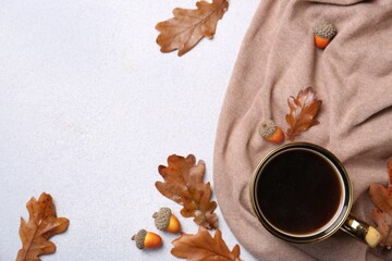 Flat lay composition with cup of hot drink and autumn leaves on light grey textured table. Space...