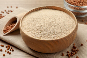 Bowl with buckwheat flour and seeds on wooden table, closeup