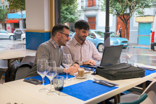 Two Men Work Together Remotely From A Restaurant