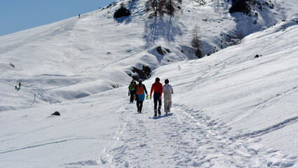 a family walks in the snow in the high mountains on a beautiful sunny winter day
