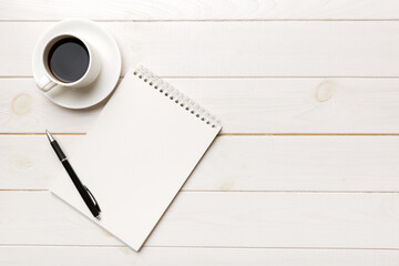 Modern office desk table with notebook and other supplies with cup of coffee. Blank notebook page for you design. Top view, flat lay