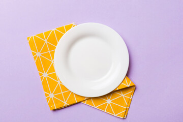 Top view on colored background empty round white plate on tablecloth for food. Empty dish on napkin with space for your design