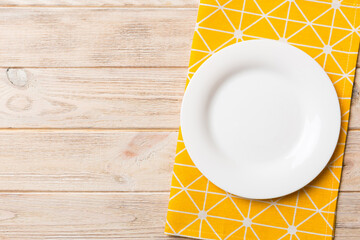 Top view on colored background empty round white plate on tablecloth for food. Empty dish on napkin with space for your design