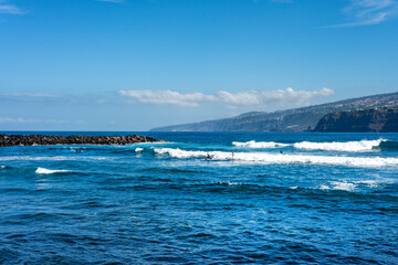 Young people surfing on the coast of Puerto de la Cruz, in Tenerife. Canary Islands. Spain.