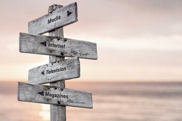media internet television magazines text written on wooden signpost outdoors at the beach during...
