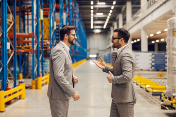 Business partners talk and negotiate while standing in storage.