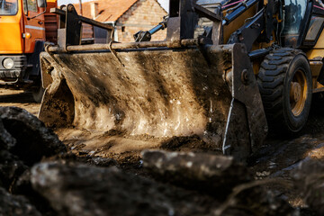 Close up of excavator digging asphalt on construction site.