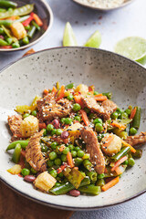 Wok with turkey meat, corn, green peas, green beans and carrots served on gray background. Asian food concept of street food