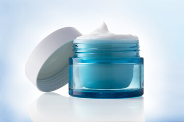 white beauty cosmetic cream in blue glass jar on light blue.