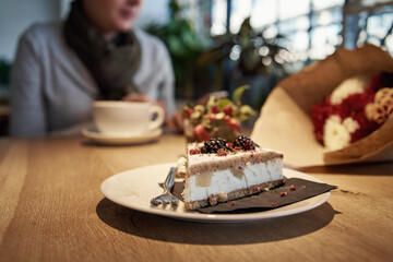 Sweet cake in a cafe with a women having coffee and looking at her mobile phone