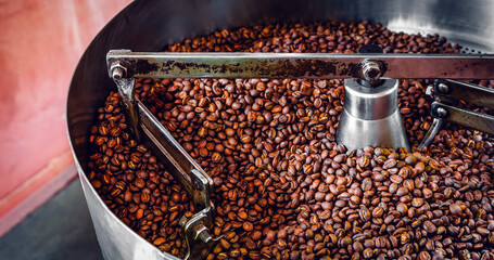 Freshly roasted aromatic coffee beans over a modern coffee roasting machine.