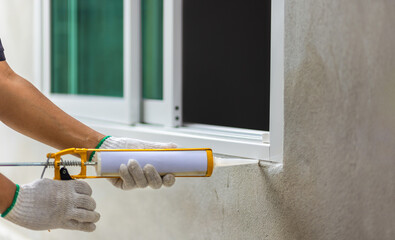 Construction worker using silicone sealant caulk the outside window frame.