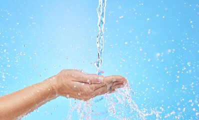 Hand, water and cleaning with a splash in studio on a blue background for hygiene or hydration. Mockup, health and wellness with a female washing under a water splash in the bathroom for skincare