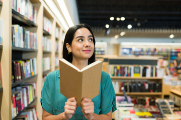Happy woman enjoying an interesting novel at the book shop