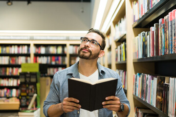 Happy man enjoying an exciting book while reading at the bookstore