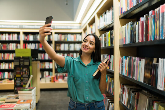 Excited woman reader posting a picture with a book on social media