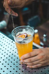 The bartender prepares a cocktail with passion fruit in a plastic glass