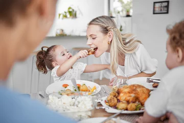 Fotobehang Happy family, mother and child eating chicken and vegetables in a healthy meal for dinner in Germany, Berlin. Food, nutrition and young girl feeding her hungry mom lunch at a home dining room table © L Ismail/peopleimages.com