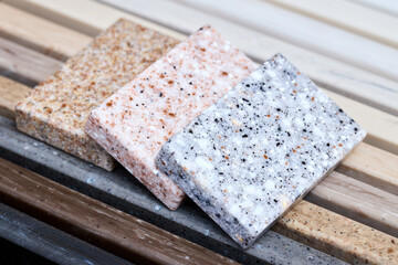 Porcelain three stoneware artificial stone square samples laid on kitchen countertop examples of future kitchen fasade exterior. Samples slabs of natural granite marble quartz for stone countertops.