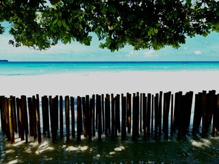 View of the turquoise waters of Boracay framed by bamboo poles and tree canopy