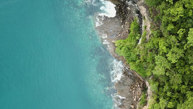 Drone footage of steep cliffs with lush green vegetation overlooking El Jobo beach in Costa Rica