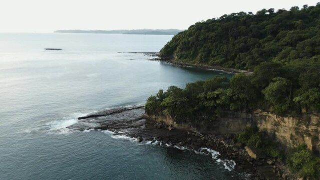 Drone footage of steep cliffs with lush green vegetation overlooking El Jobo beach in Costa Rica