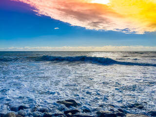 Ocean water splash on rock beach with beautiful sunset sky and clouds.  Sea wave splashing on stone at sea shore