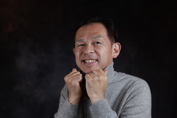 Middle-aged Japanese man in gray turtleneck wool sweater. Concept image of Warm Biz, stability in daily life, and sustainable living.