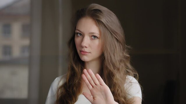 Close-up young serious caucasian woman teenager showing stop gesture with hand to camera protesting against violence demonstrating no to abuse of female making prohibition sign shows disagreement
