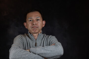 Middle-aged Japanese man in gray turtleneck wool sweater. Concept image of Warm Biz, stability in...