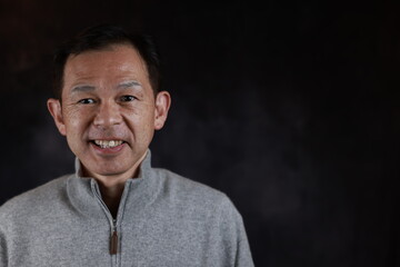 Middle-aged Japanese man in gray turtleneck wool sweater. Concept image of Warm Biz, stability in daily life, and sustainable living.