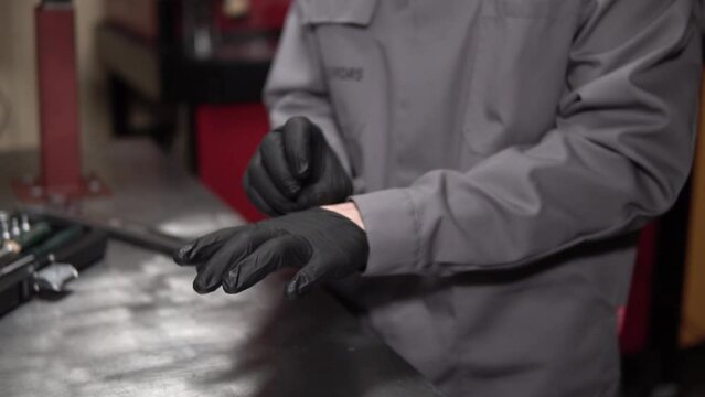 mechanic Man Wears Black Leather Gloves. mechanic puts black latex gloves on his hands.hygiene concept