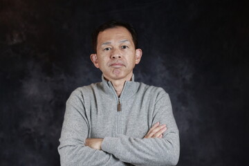 Middle-aged Japanese man in gray turtleneck wool sweater. Concept image of Warm Biz, stability in daily life, and sustainable living.