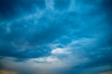 Naklejka na ściany i meble Sunset sky in bright blue tones. A wide panorama of the evening sky covered with dark clouds. Background with impending bad weather in anticipation of rain.