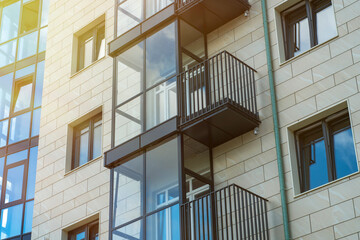 The wall of a modern residential building with glazed balconies. New inexpensive housing for young...