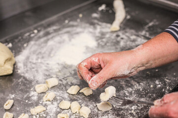 person kneading dough for gnocchi on table