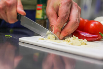 chef cutting garlic in a kitchen