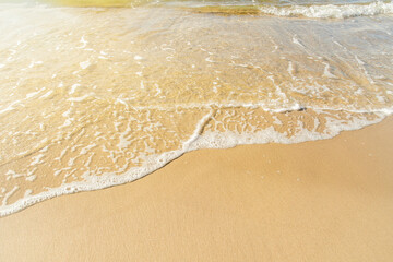Fototapeta na wymiar Close-up of a beach with a calm transparent wave. Romantic sea coast with golden sand.