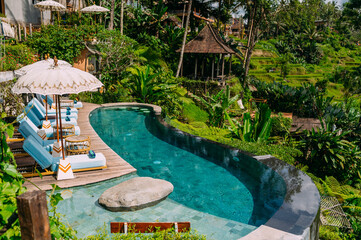 Blick auf das Schwimmbad Wasser und Sonnenliegen im tropischen Dschungel in der Nähe von Ubud, Bali, Indonesien
