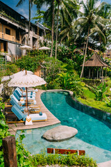 Blick auf das Schwimmbad Wasser und Sonnenliegen im tropischen Dschungel in der Nähe von Ubud, Bali, Indonesien