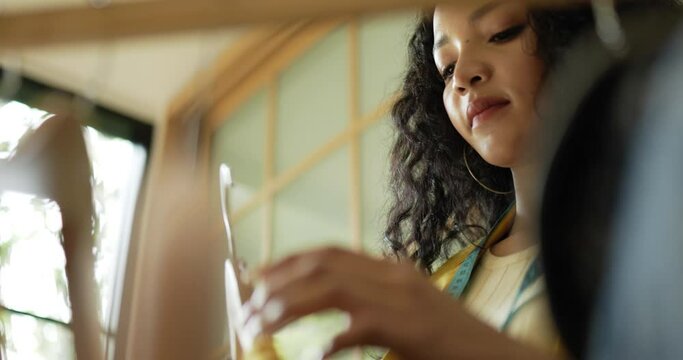 Handheld close up shot, Young beautiful woman fashion designer checking beautiful clothes on hanger in shop and smile with happy, Startup small business entrepreneur concept