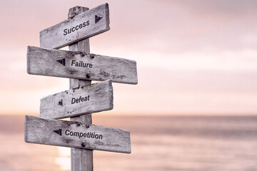 success failure defeat competition text written on wooden signpost outdoors at the beach during sunset